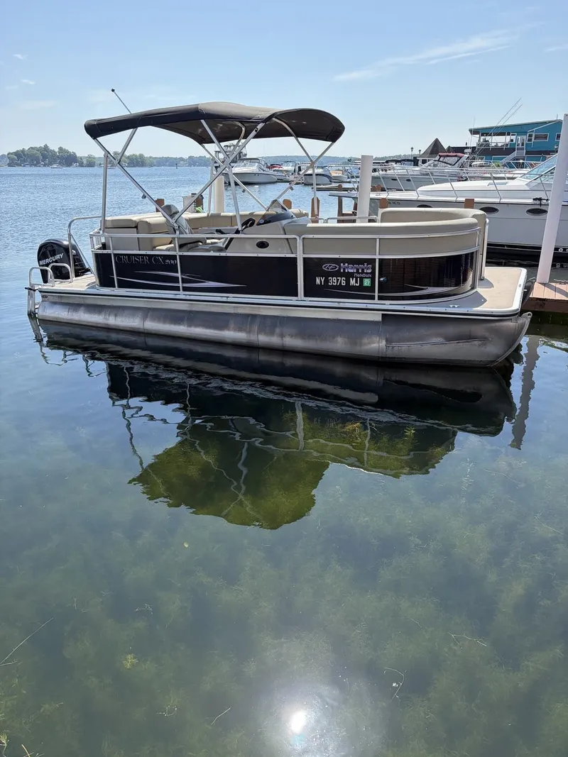 The Image of A 2012 Harris FloteBote Cruiser 200 CX200 is docked by the water. - 1
