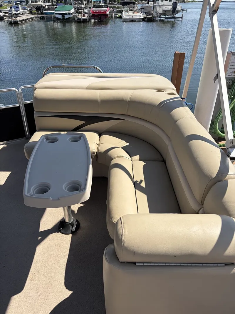 Slide: The Image of A 2012 Harris FloteBote Cruiser 200 CX200 with beige seating and table, docked by the water. - 3