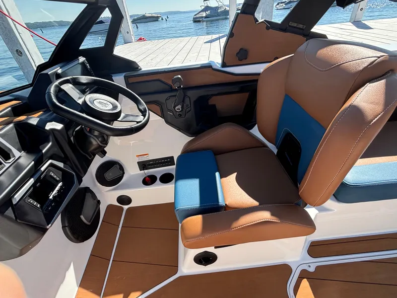 Slide: The Image of The image shows the interior of a 2026 Axis A225 boat with brown and blue seating. - 946