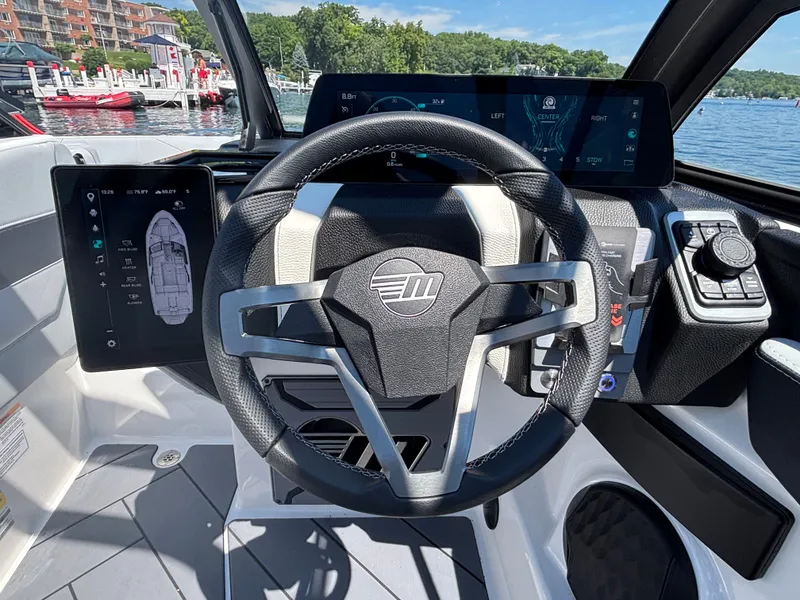 Slide: The Image of The image shows the cockpit of a Malibu Wakesetter 23 LSV with a modern steering wheel and digital displays. - 889