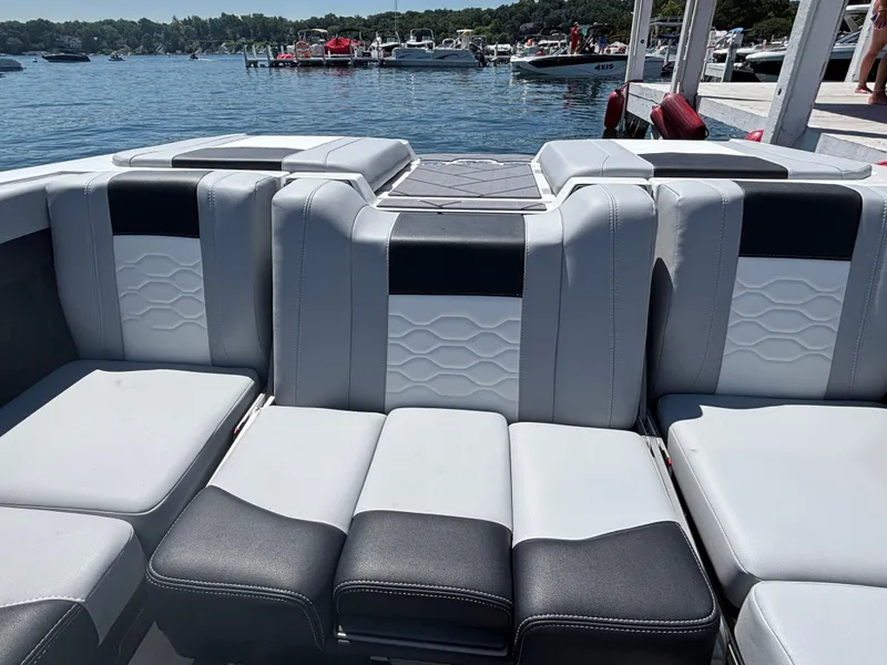 Slide: The Image of The 2026 Malibu Wakesetter 23 LSV features luxurious, cushioned seating in a modern design by the water. - 887
