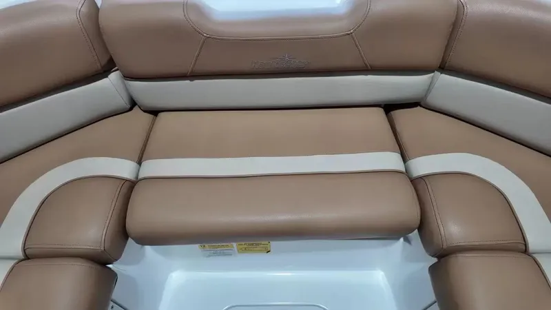 Slide: The Image of The 2023 NauticStar 243 DC features a luxurious, cushioned seating area in brown and beige. - 23