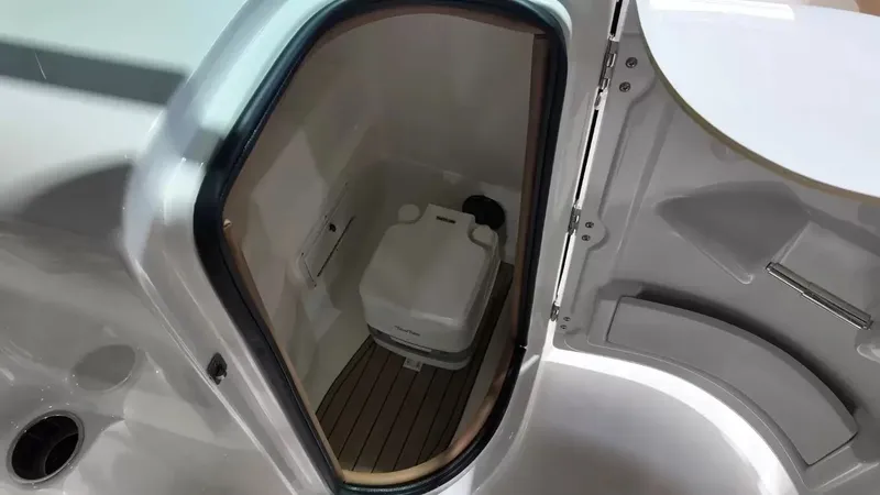 Slide: The Image of The image shows a compact boat toilet with a wooden floor and a white door. - 45