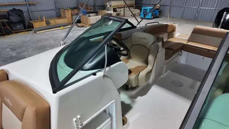 Slide: The Image of The image shows the cockpit of a 2023 NauticStar 243 DC boat with beige seating. - 32