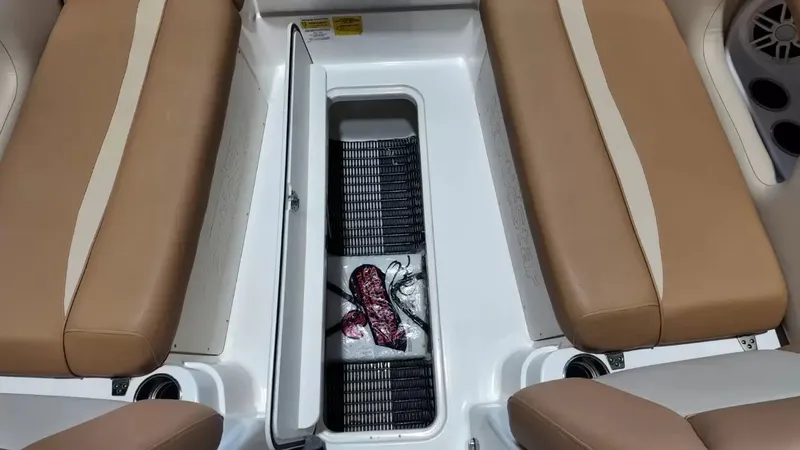 Slide: The Image of The image shows the interior of a NauticStar 243 DC boat with brown seats and an open storage compartment. - 30