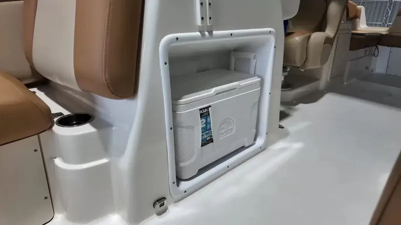 Slide: The Image of Interior of a NauticStar 243 DC featuring a built-in cooler and beige seating. - 31