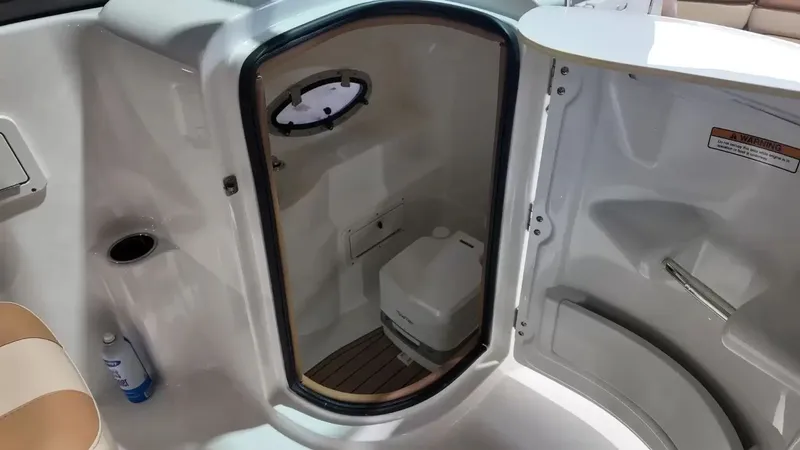 Slide: The Image of Interior view of a NauticStar 243 DC featuring a small toilet and a porthole. - 46