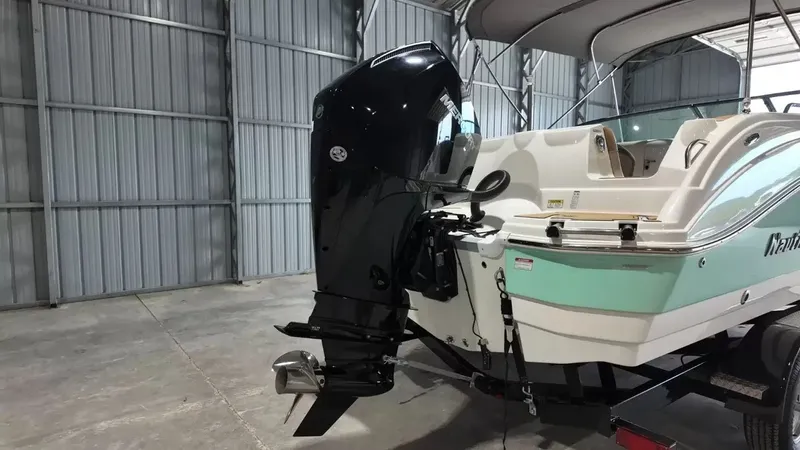 Slide: The Image of A 2023 NauticStar 243 DC boat in a storage facility. It features an outboard motor and two-tone paint. - 6