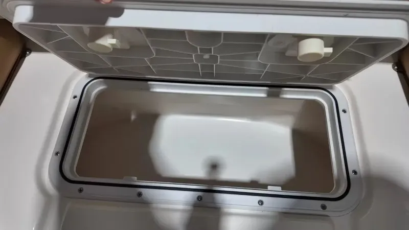 Slide: The Image of An open storage compartment lid on a boat, revealing an empty, rectangular interior. - 25