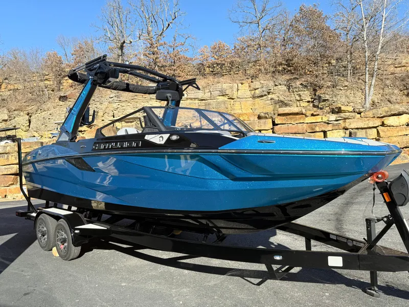 Slide: The Image of A blue Centurion Fe22 boat from 2026 on a trailer in front of a rocky wall. - 13