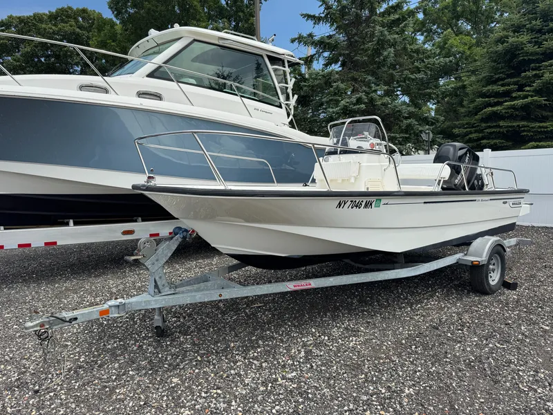 The Image of A 2014 Boston Whaler 170 Montauk on a trailer beside a larger boat. - 1