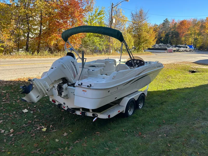 Slide: The Image of A 2003 Bennington RL210 boat on a trailer, set on grass, surrounded by autumn trees. - 5