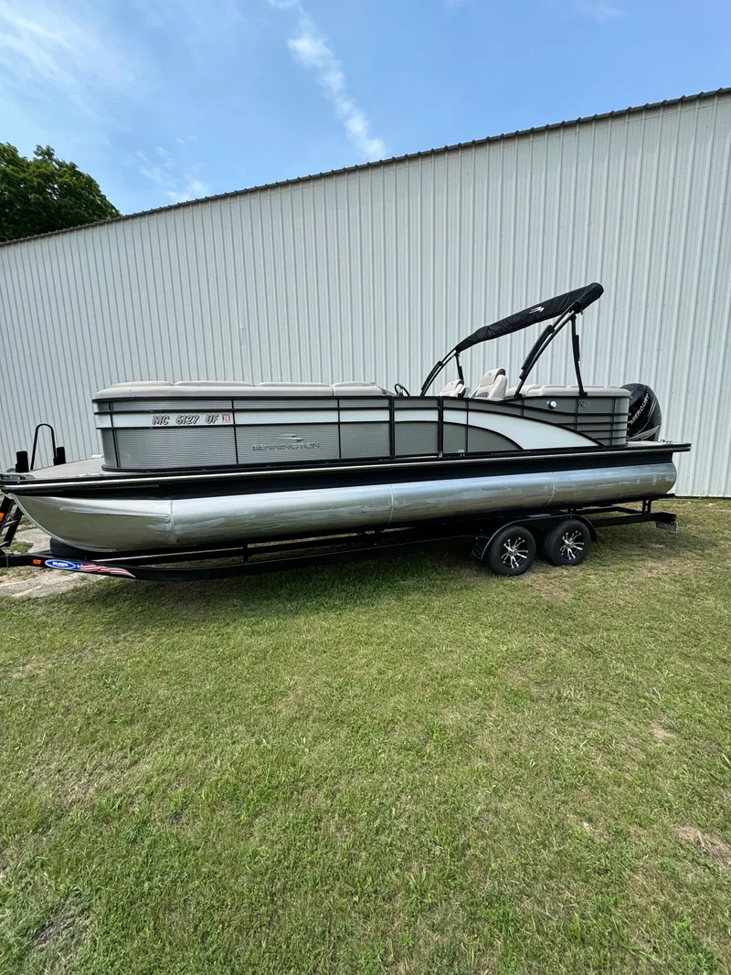Slide: The Image of A 2019 Bennington 25RSR pontoon boat on a trailer beside a building. - 2