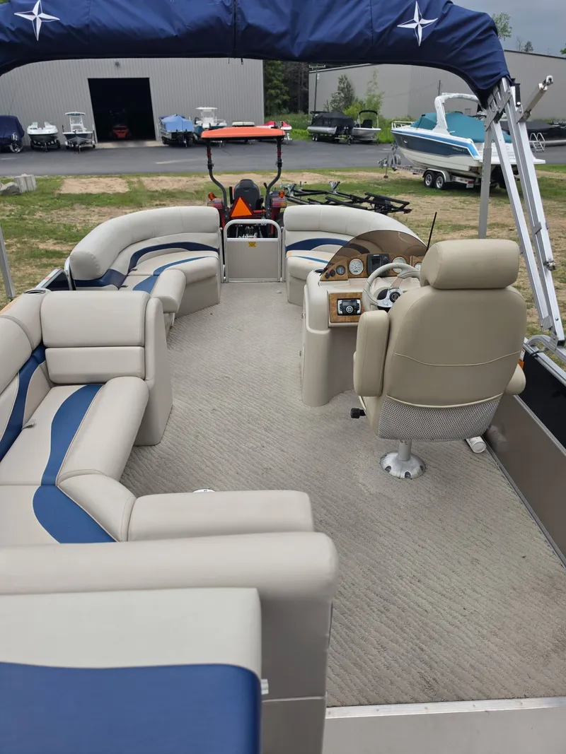 Slide: The Image of The image shows the interior of a 2012 Berkshire 231RF pontoon boat with beige and blue seating. - 15