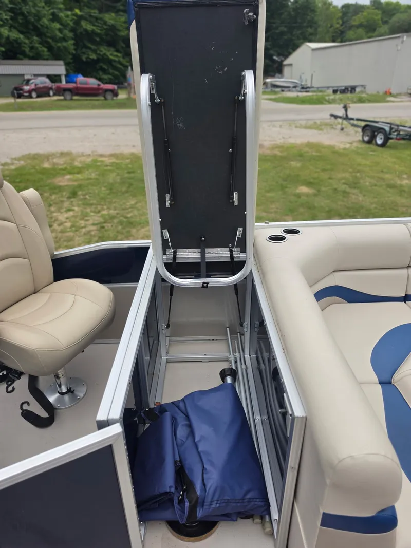 Slide: The Image of An open storage compartment on a boat with blue bags and beige seats. - 16