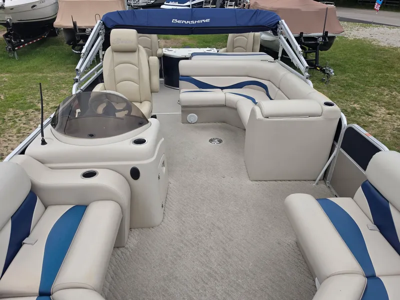 Slide: The Image of The image shows the interior of a Berkshire 231RF pontoon boat with beige and blue seating. - 7