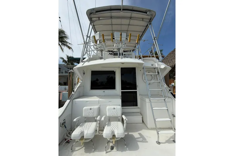 Slide: The Image of 1989 Bertram 43 Convertible yacht with fishing chairs and ladder, docked under clear skies. - 26