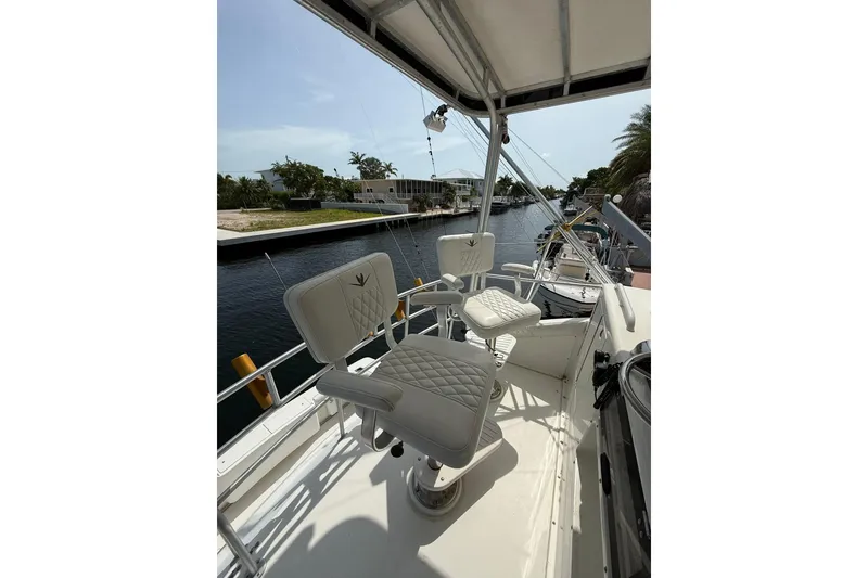 Slide: The Image of 1989 Bertram 43 Convertible yacht with white captain chairs on deck, docked by a canal. - 49
