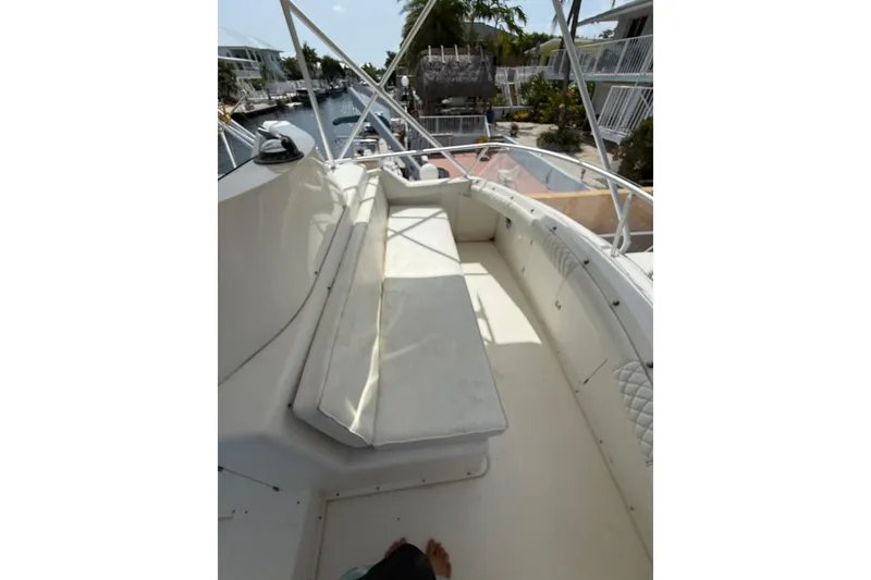 Slide: The Image of 1989 Bertram 43 Convertible boat deck with seating, docked near waterfront homes. - 54