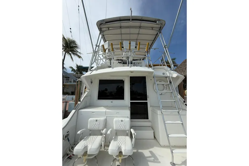 Slide: The Image of 1989 Bertram 43 Convertible yacht with fishing chairs and ladder, docked under clear skies. - 27