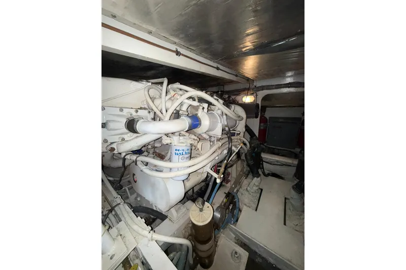 Slide: The Image of Engine room of a 1989 Bertram 43 Convertible yacht, showcasing complex machinery and piping. - 59