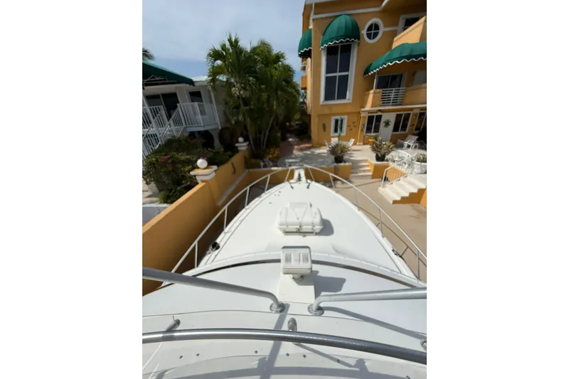 Slide: The Image of 1989 Bertram 43 Convertible yacht docked near a yellow building with green awnings. - 56