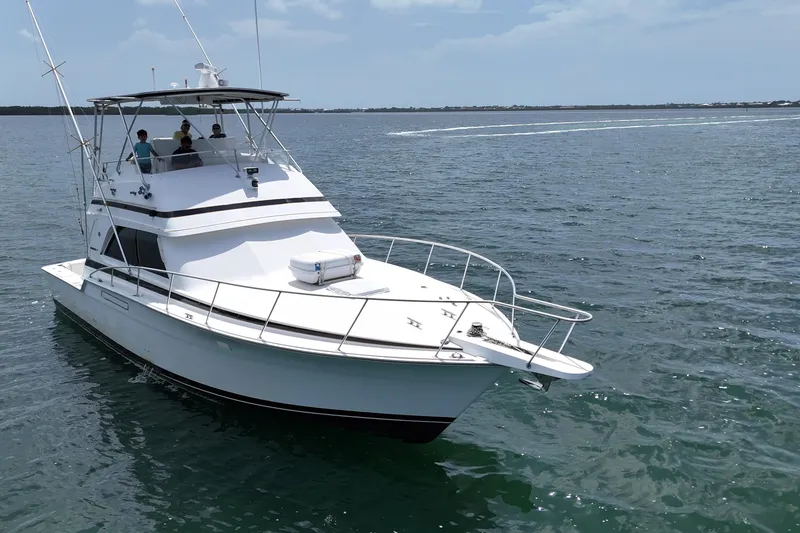 Slide: The Image of 1989 Bertram 43 Convertible yacht cruising on open water under a clear sky. - 11