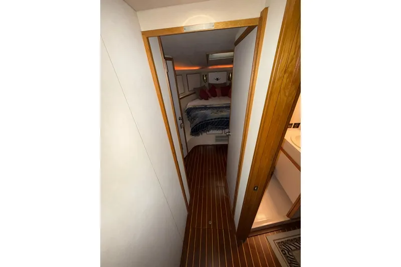 Slide: The Image of Interior hallway of 1989 Bertram 43 Convertible yacht with wood accents and cozy bedroom. - 43
