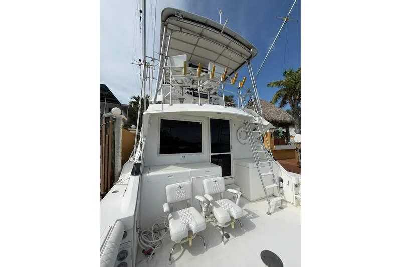Slide: The Image of 1989 Bertram 43 Convertible yacht with fishing chairs and ladder, docked near palm trees. - 25