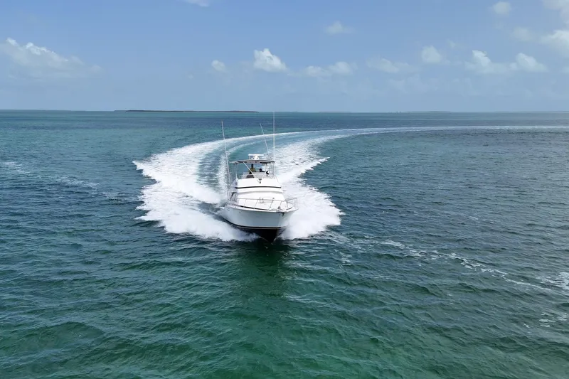 Slide: The Image of 1989 Bertram 43 Convertible yacht cruising on open sea under clear skies. - 5