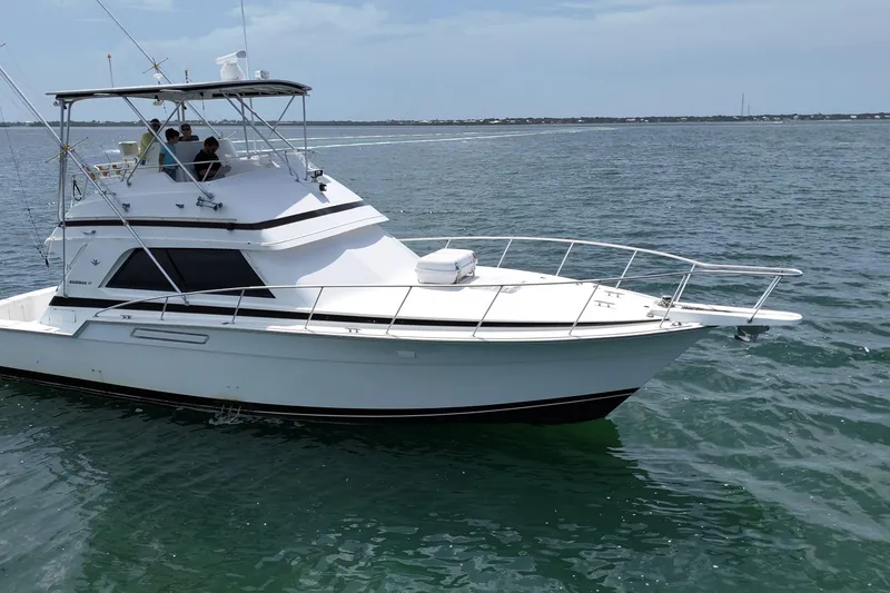 Slide: The Image of 1989 Bertram 43 Convertible yacht cruising on open water under a clear sky. - 10