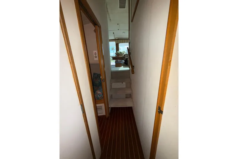 Slide: The Image of Narrow hallway inside 1989 Bertram 43 Convertible yacht with wooden accents and carpeted stairs. - 46