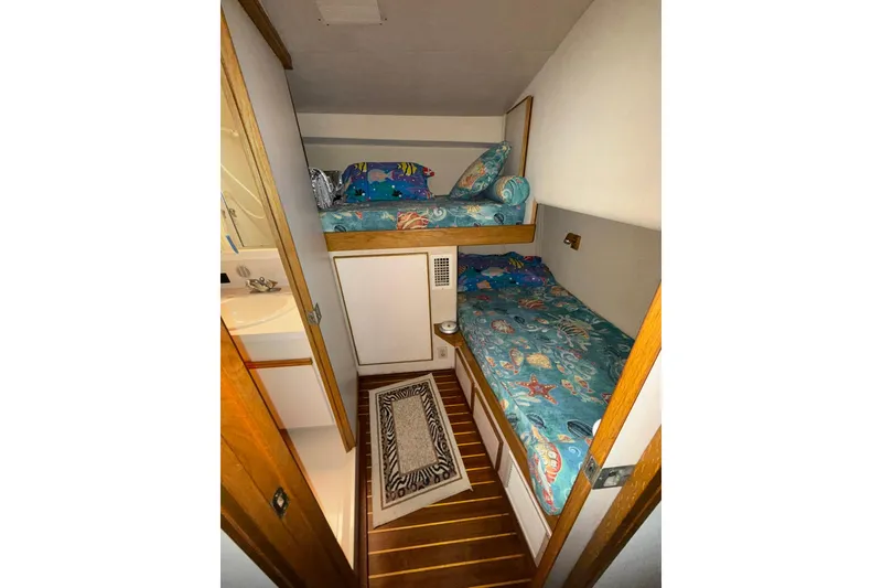 Slide: The Image of 1989 Bertram 43 Convertible cabin with bunk beds and nautical-themed bedding. - 41