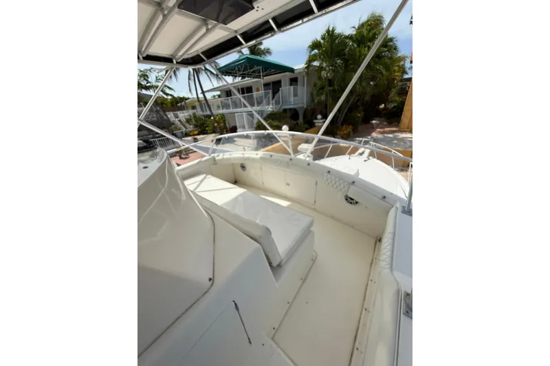 Slide: The Image of 1989 Bertram 43 Convertible boat deck with seating, surrounded by tropical greenery. - 53