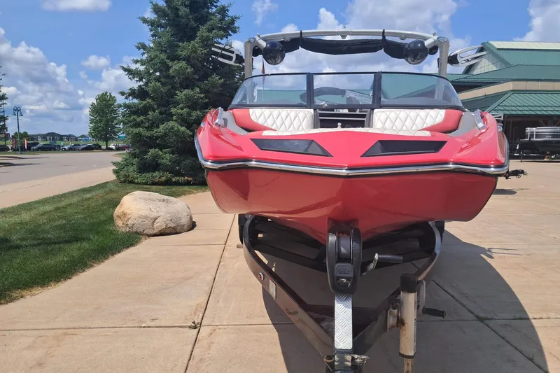 Slide: The Image of 2013 Tigé RZ2 boat in vibrant red on a trailer, parked outdoors. - 1