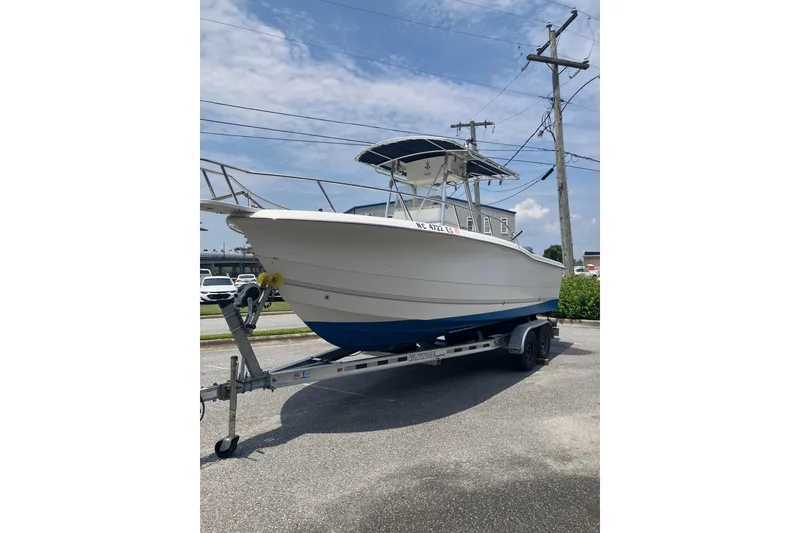The Image of 2003 Seapro 239 boat on trailer, white hull with blue bottom, parked outdoors. - 2
