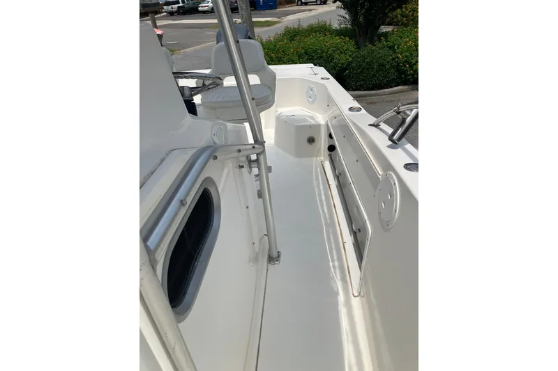 Slide: The Image of 2003 Seapro 239 boat interior with seating and railing, parked near greenery. - 13