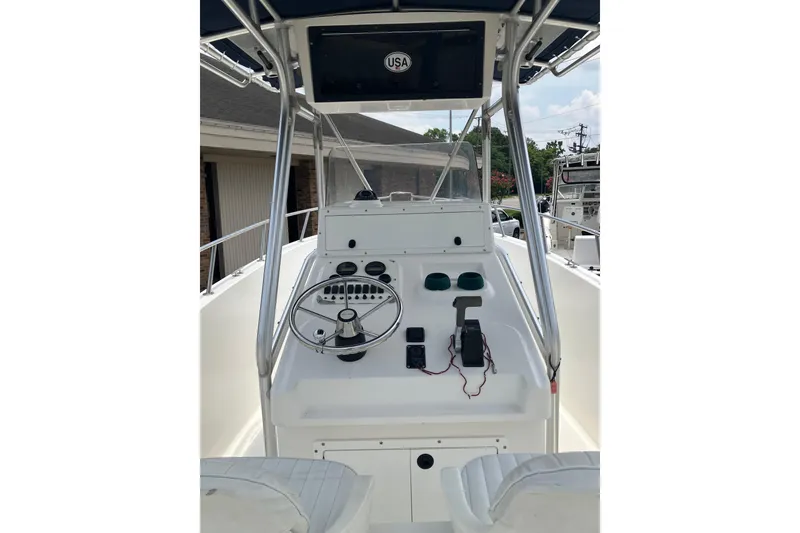 Slide: The Image of 2003 Seapro 239 boat dashboard with steering wheel and controls, under a canopy. - 4