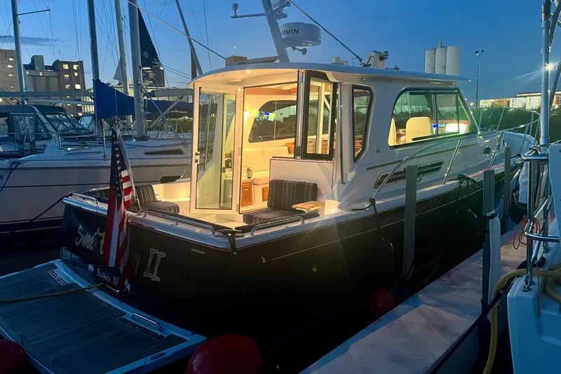 Slide: The Image of 2024 Back Cove 372 yacht docked at night, illuminated interior, American flag displayed. - 4