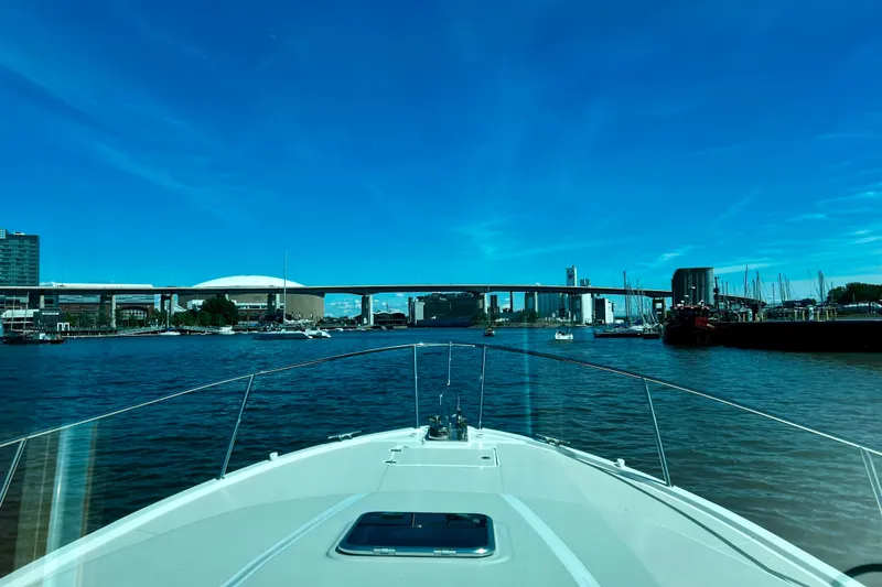 Slide: The Image of 2024 Back Cove 372 cruising in a vibrant city harbor under a clear blue sky. - 10
