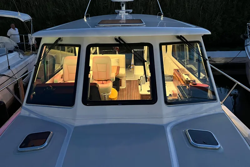 Slide: The Image of 2024 Back Cove 372 boat interior view at dusk, showcasing elegant seating and design. - 21