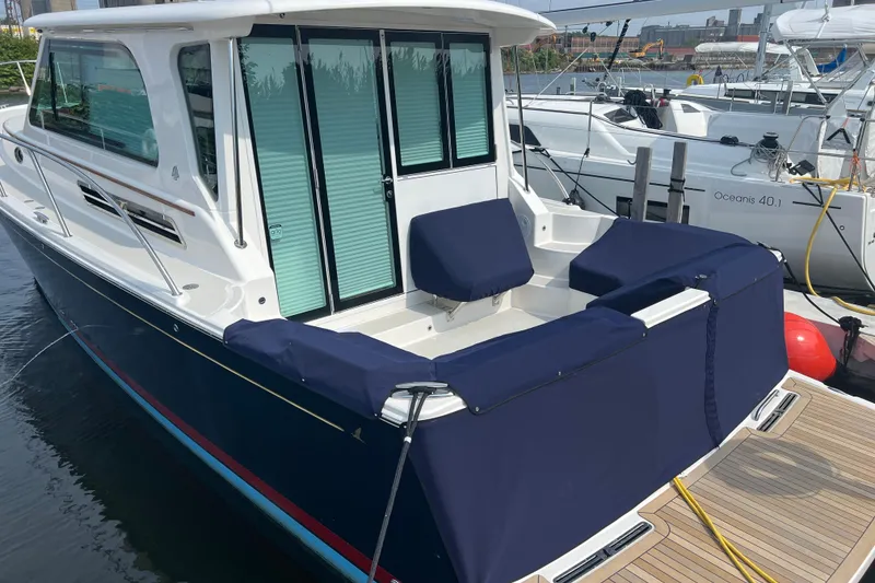 Slide: The Image of 2024 Back Cove 372 yacht docked, featuring a sleek design and covered seating area. - 13