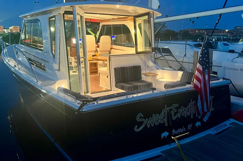 Slide: The Image of 2024 Back Cove 372 yacht docked at night, illuminated interior, American flag displayed. - 3