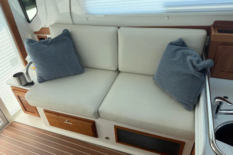 Slide: The Image of 2024 Back Cove 372 interior with cushioned seating and pillows, featuring wooden accents. - 56