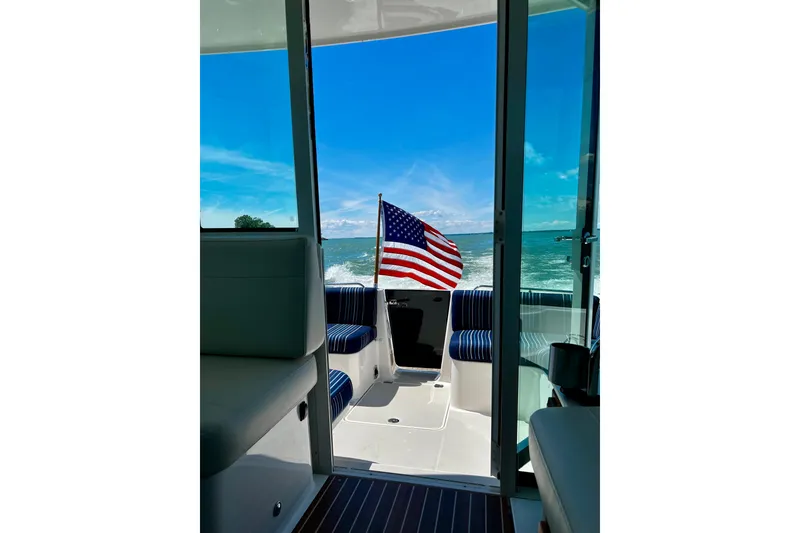 Slide: The Image of 2024 Back Cove 372 boat interior with American flag, ocean view, and blue sky. - 9
