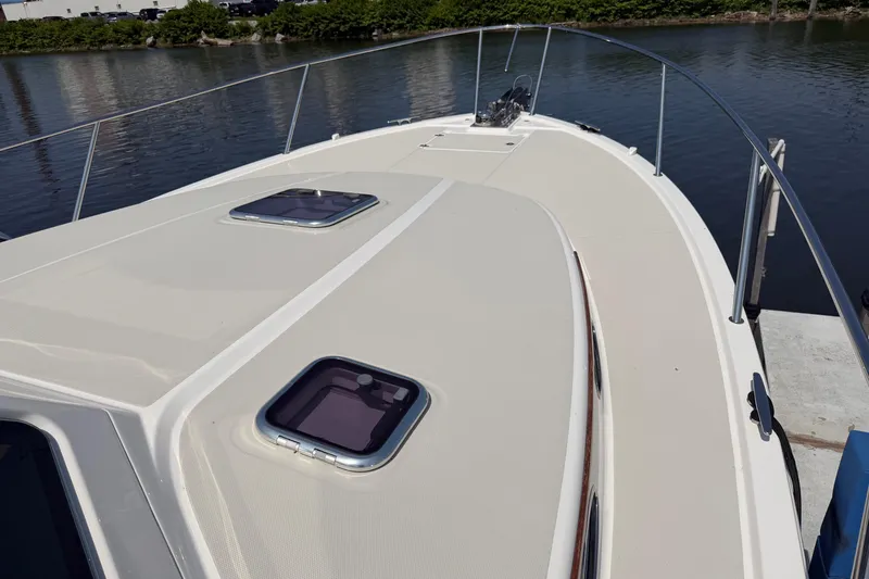 Slide: The Image of 2024 Back Cove 372 boat deck with hatches, docked by calm water. - 64