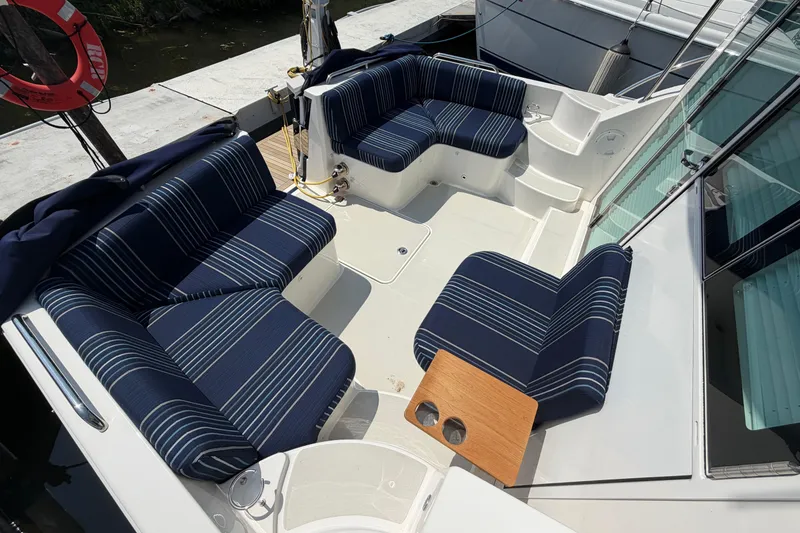 Slide: The Image of 2024 Back Cove 372 boat deck with striped seating and wooden table. - 75
