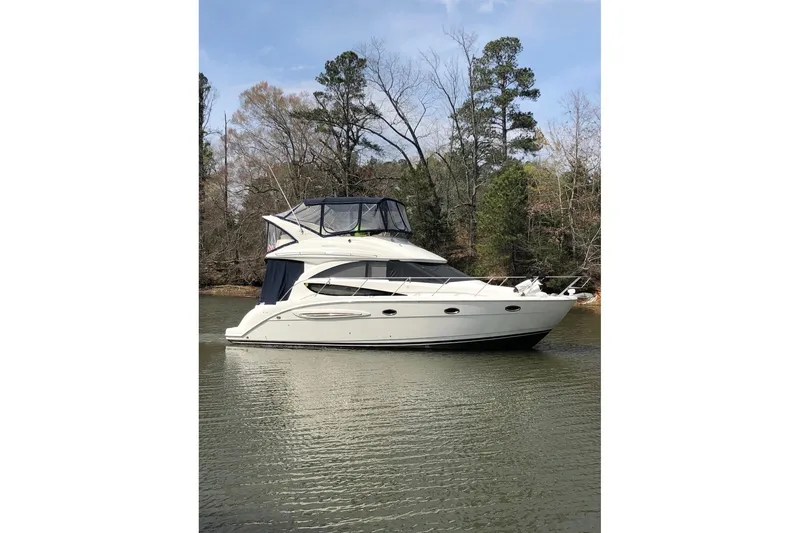 The Image of 2006 Meridian 341 Sedan yacht on calm water, surrounded by trees. - 0