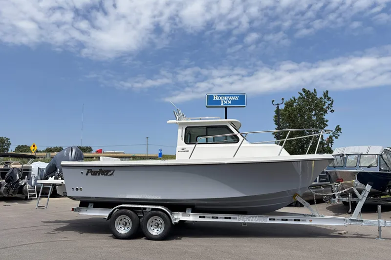 The Image of 2027 Parker 227 Explorer boat on trailer, parked near Rodeway Inn under a partly cloudy sky. - 0