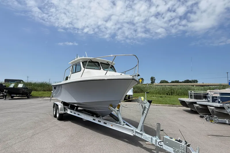 Slide: The Image of 2027 Parker 227 Explorer boat on trailer under a clear blue sky. - 2